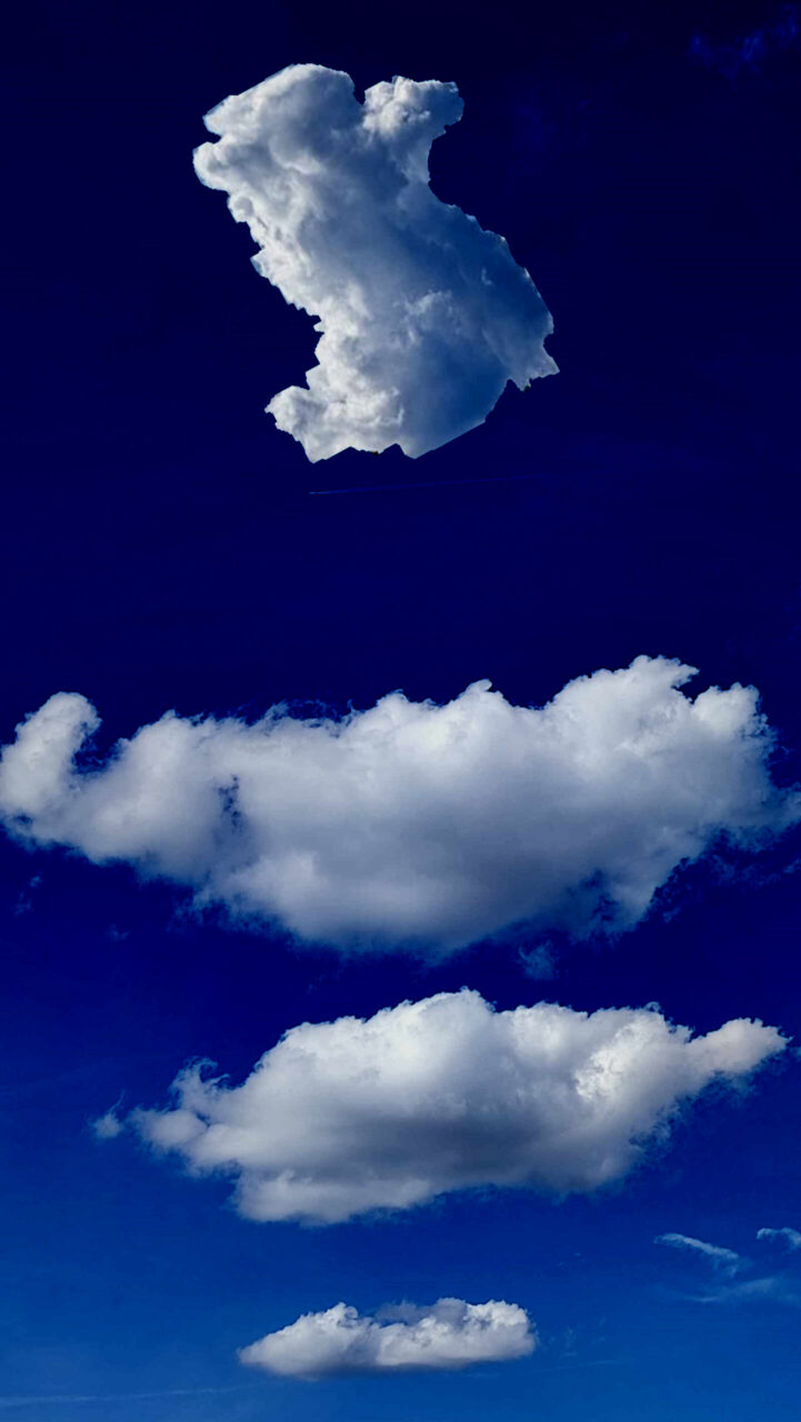 Drei Treppenwolken. Die unterste ist die Kleinste, die näheste die Größte. Darüber fliegt die Wolkenfigur, das Alpaka Cloudurjan. Alles das im mittel-kobaltblauen Himmel aus Flugzeughöhe.