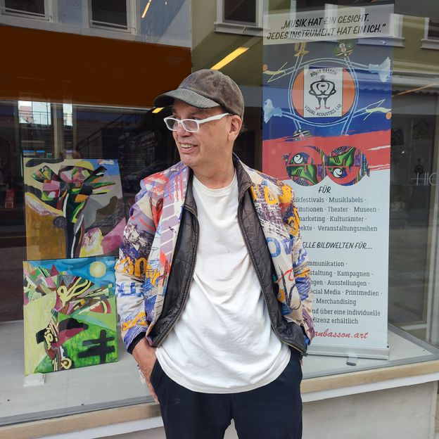 Bojan Basson vor dem rechten Schaufenster des Jugendstil-Ausstellungsraums, dahinter rechts sein Rollup zu VISUAL ACOUSTICS LAB, links zwei Ölbilder von ihm